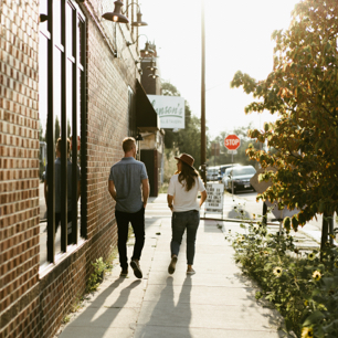 couple walking down a sidewalk in sunlight